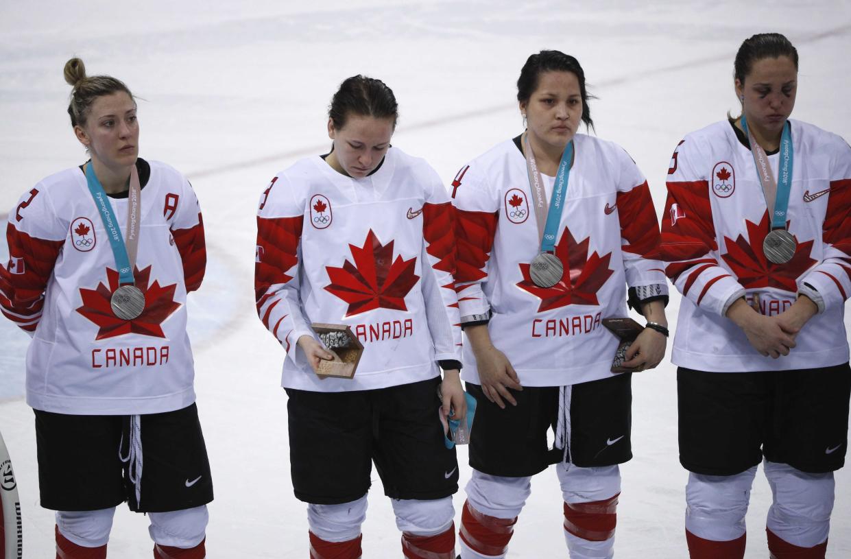 Jocelyne Larocque (second from right) holds her silver medal in her hand, next to teammates wearing their medals during the medal ceremony. (REUTERS/Brian Snyder)