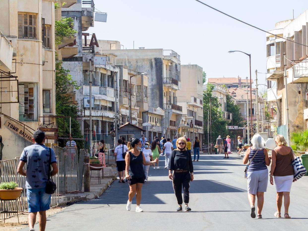 Visitors walk on a street lined with derelict buildings at the fenced-off beachfront eastern town of Varosha in October 2020.