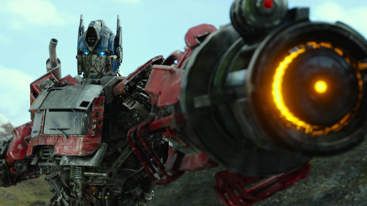  Optimus Prime aiming a large canon at the camera in Transformers: Rise of the Beasts. 