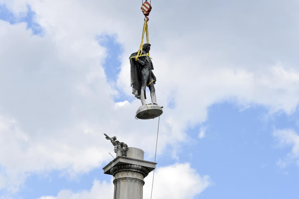 The statue of former U.S. vice president and slavery advocate John C. Calhoun hovers above its monument after contractors completed a 17-hour removal process on Wednesday, June 24, 2020, in Charleston, S.C. (AP Photo/Meg Kinnard)