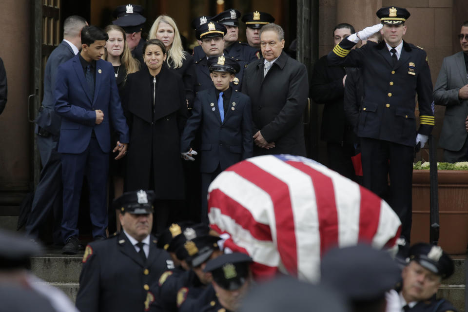 The family of Jersey City Police Detective Joseph Seals, including his wife Laura Seals, center left, watch as his casket is carried out of the church in Jersey City, N.J., Tuesday, Dec. 17, 2019. The 40-year-old married father of five was killed in a confrontation a week ago with two attackers who then drove to a kosher market and killed three people inside before dying in a lengthy shootout with police. (AP Photo/Seth Wenig)