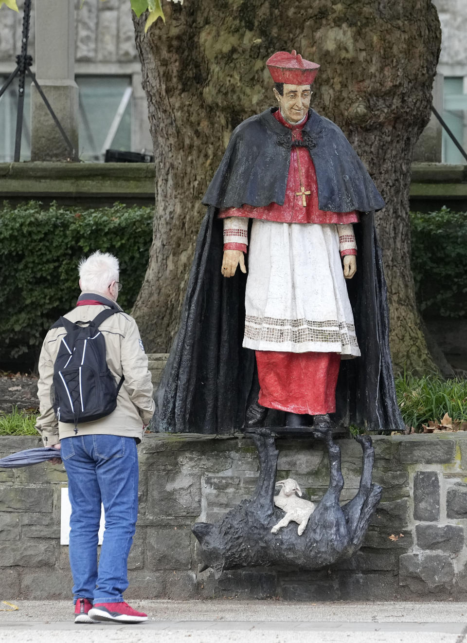 A man watches the monument of German cardinal Franz Hengsbach beside the cathedral in the city center of Essen, western Germany, Friday, Sept. 22, 2023. The Catholic Church is investigating allegations of sexual abuse by the late cardinal over 30 years after his death. (AP Photo/Martin Meissner)