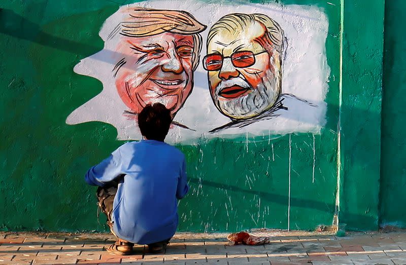 A man applies finishing touches to paintings of U.S. President Trump and India's PM Modi along a route that Trump and Modi will be taking during Trump's upcoming visit, in Ahmedabad