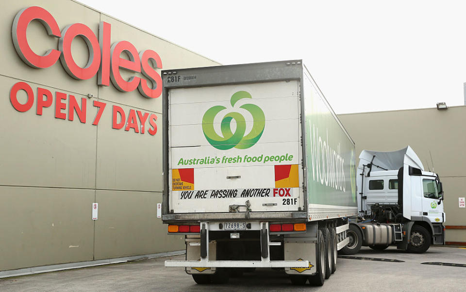 A Woolworths truck parked outside a Coles store. 