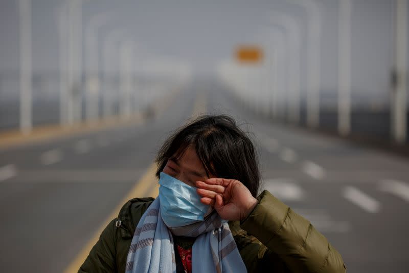 A mother reacts as she pleads with police to allow her daughter to pass a checkpoint for cancer treatment after she arrived from Hubei province at the Jiujiang Yangtze River Bridge in Jiujiang