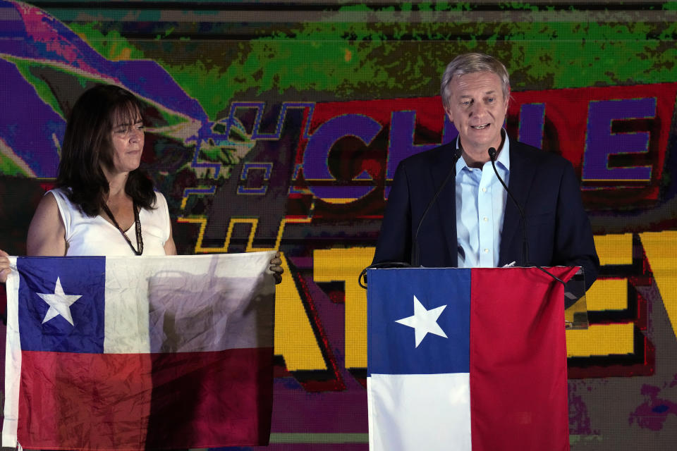 Republican Party presidential candidate Jose Antonio Kast speaks to supporters alongside his wife Maria Pia Adriasola at his campaign headquarters after polls closed and partial results were announced in Santiago, Chile, Sunday, Nov. 21, 2021. (AP Photo/Esteban Felix)