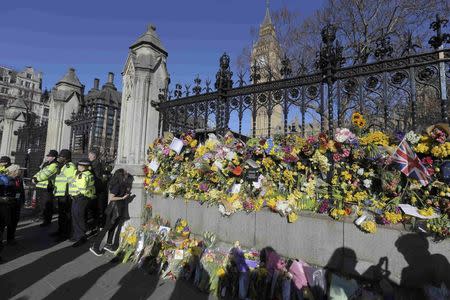 Onlookers view floral tributes on the wall surrounding the Houses of Parliament, following the attack in Westminster earlier in the week, in central London, Britain March 25, 2017. REUTERS/Paul Hackett