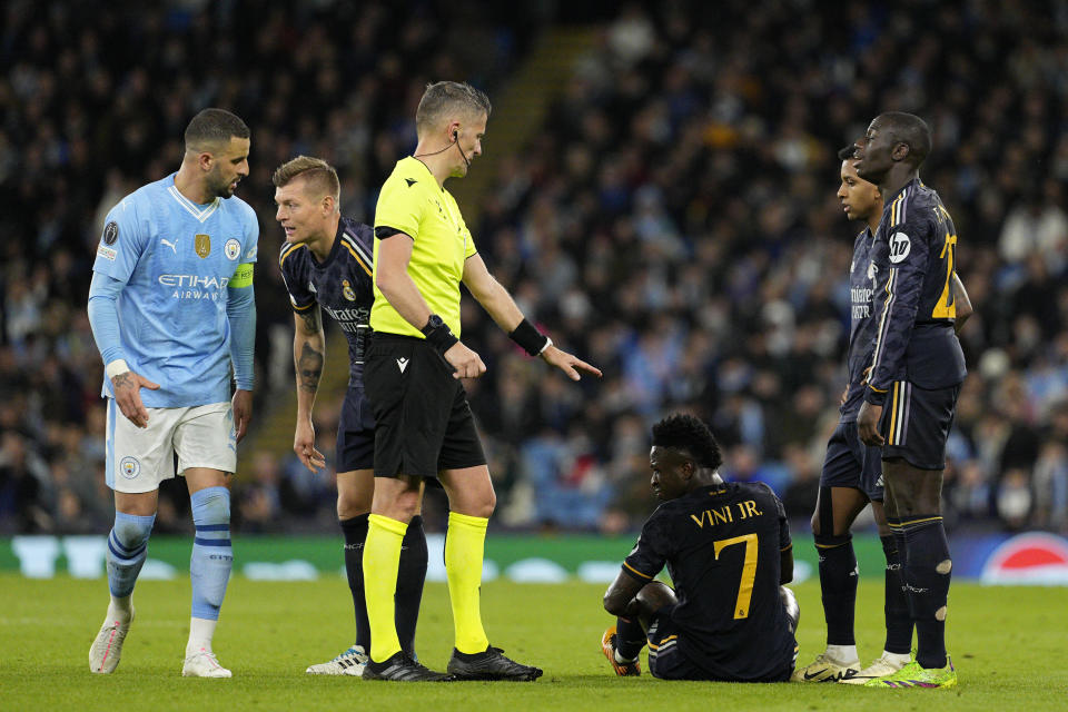 Real Madrid's Vinicius Junior, bottom, lies on the ground after being tackled by Manchester City's Kyle Walker, left, during the Champions League quarterfinal second leg soccer match between Manchester City and Real Madrid at the Etihad Stadium in Manchester, England, Wednesday, April 17, 2024. (AP Photo/Dave Shopland)