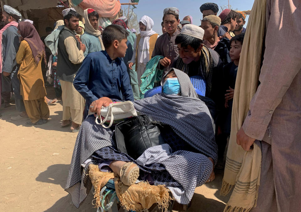 A porter pushes a wheelbarrow carrying an elderly Afghan woman with her family as they enter into Pakistan from Afghanistan at a border crossing, in Chaman, Pakistan, Thursday, Aug. 19, 2021. Chaman, is a key border crossing between Pakistan and Afghanistan, normally thousands of Afghans and Pakistanis cross daily and a steady stream of trucks passes through, taking goods to Afghanistan. (AP Photo)