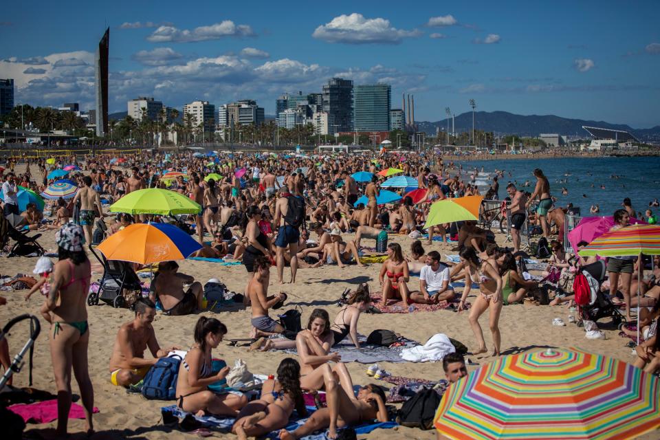 People enjoy the warm weather on the beach in Barcelona, Spain, Saturday, June 13, 2020. Spanish government has announced that the northwestern region of Galicia will move next week to what the government calls "the new normal," when some rules, such as wearing face masks when social distancing is not possible, will remain in place. (AP Photo/Emilio Morenatti)