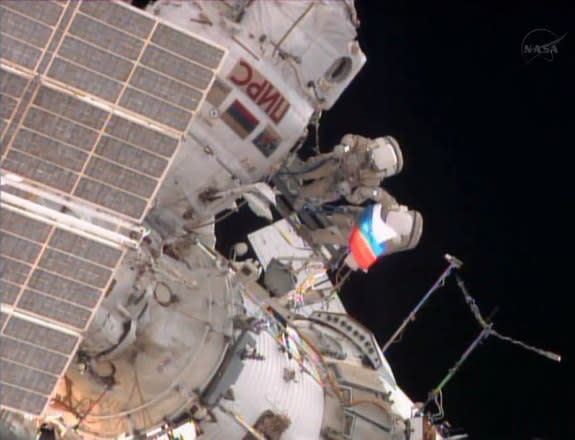 A cosmonaut unfurls a Russian flag outside the International Space Station during a spacewalk on Aug. 22, 2013, to mark Russian Flag Day.