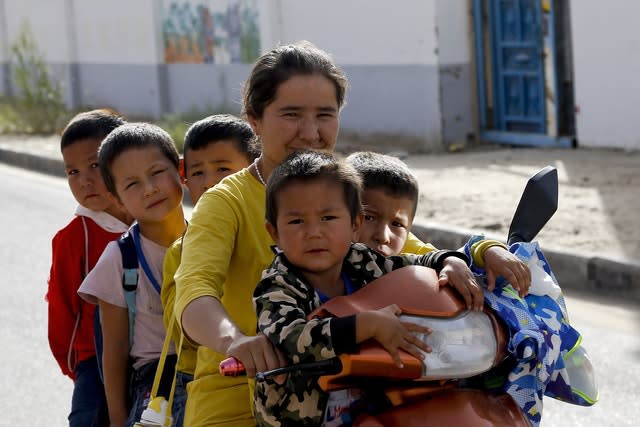 A Uighur woman and children sit on a motor-tricycle after school (Andy Wong/AP)