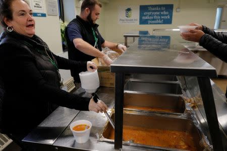 Francine Walsh and Ritchie Sullivan serve fish soup and sandwiches for lunch to homeless men sheltering in the Pine Street Inn in Boston, Massachusetts, U.S., January 5, 2018. REUTERS/Brian Snyder