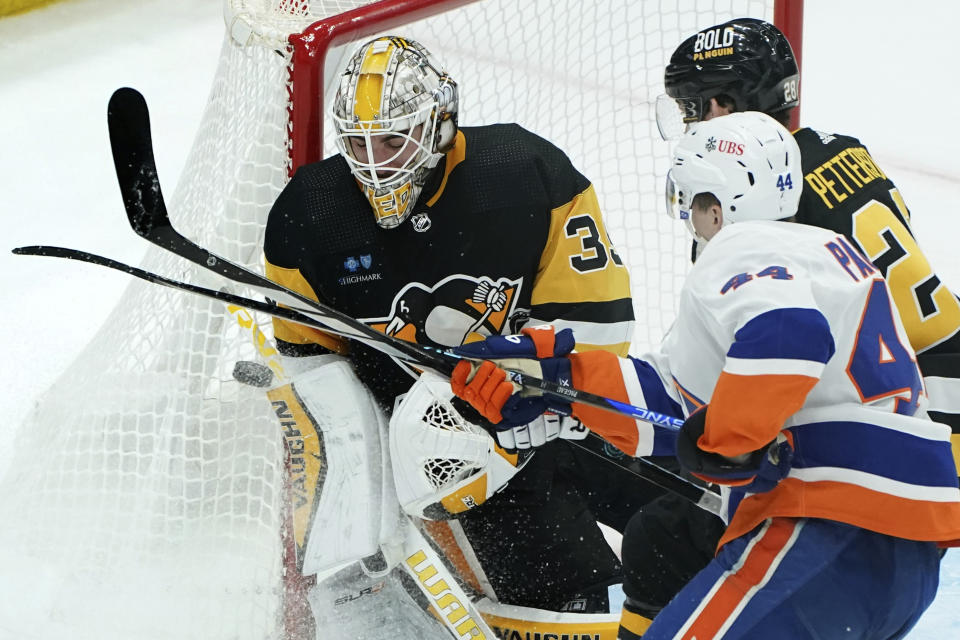 Pittsburgh Penguins goaltender Alex Nedeljkovic, left, reaches to deflect a shot by New York Islanders' Jean-Gabriel Pageau (44) during the third period of an NHL hockey game Sunday, Dec. 31, 2023, in Pittsburgh. (AP Photo/Matt Freed)