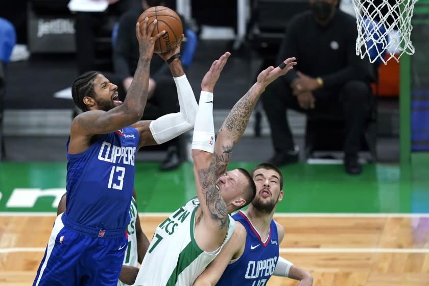 Los Angeles Clippers guard Paul George (13) shoots against Boston Celtics center Daniel Theis (27) as Clippers center Ivica Zubac (40) looks on in the first quarter of an NBA basketball game, Tuesday, March 2, 2021, in Boston. (AP Photo/Elise Amendola)