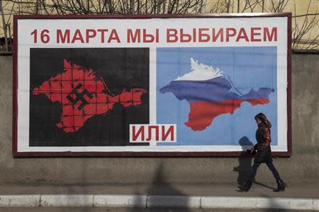 A woman walking by a poster calling people to vote in the upcoming referendum, in the Crimean port city of Sevastopol March 10, 2014. REUTERS/Baz Ratner