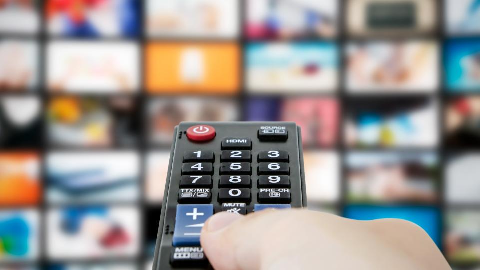  A TV remote poiting at a screen of blurry TV banner images 