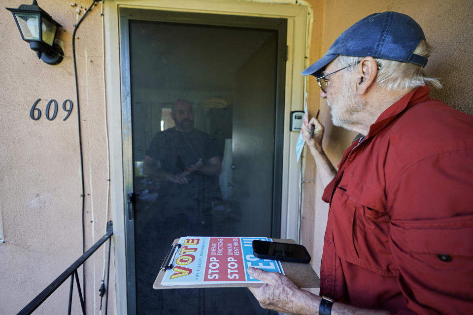 Yes on Measure H! volunteer Ed Washatka, right, visits tenant Eric Hilgart at a duplex apartment in Pasadena, Calif., Saturday, Oct. 29, 2022. Cities across the country are pushing measures to stabilize or control rents when housing prices are skyrocketing. Voters from Orange County, Florida, and in several California cities are asking voters to approve ballot measures that would cap rent increases. (AP Photo/Damian Dovarganes)
