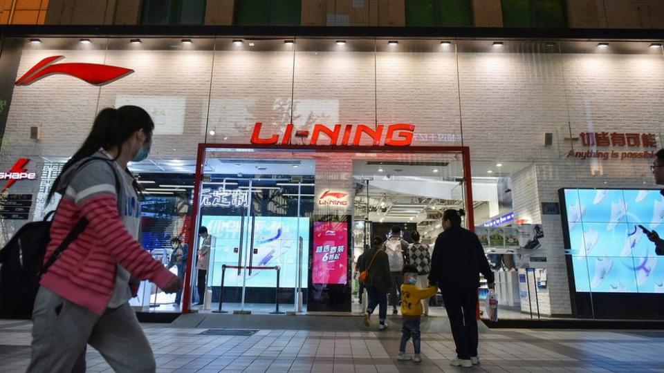 2021/04/17: A woman wearing a face mask walks past Li Ning store on Wangfujing Street.