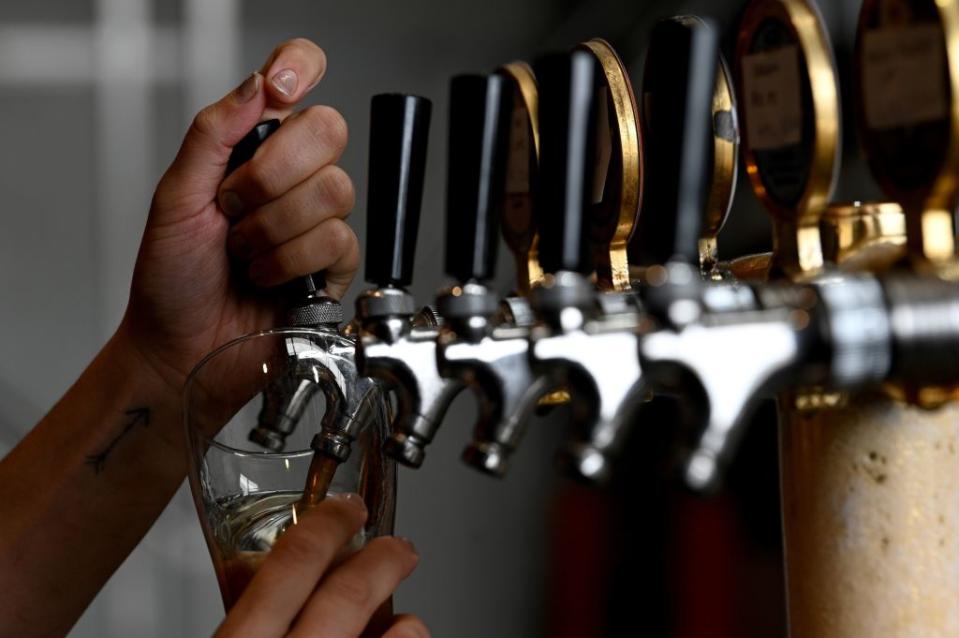 A bartender pours a glass of beer for a customer at a resturant in Sydney on May 15, 2020. - Sydney's bars and restaurants flung open their doors as a weeks-long lockdown eased Friday, but many remained quiet with only a few cautious patrons returning. (Photo by Saeed KHAN / AFP) (Photo by SAEED KHAN/AFP via Getty Images)