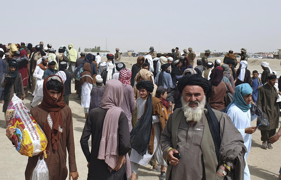 Pakistan army soldiers stand guard as stranded people gather near the Pakistan Afghan border crossing following fighting between Afghan security forces and Taliban in SpinBoldak border area, in Chaman, Pakistan, Friday, July 16, 2021. Afghan government security forces were battling to retake the southeastern SpinBoldak border crossing with neighbor Pakistan Friday, according to Afghanistan's deputy defense ministry spokesman Fawad Awan. (AP Photo/Tariq Achakzai)