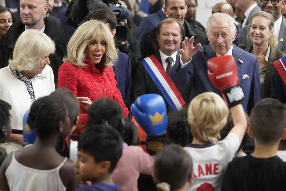 Britain's Queen Camilla , left, French President Emmanuel Macron's wife Brigitte Macron, second left, and Britain' s King Charles III talk to children exercising boxing during a visit to a gymnasium, Thursday, Sept. 21, 2023 in Saint-Denis, outside Paris. (AP Photo/Thibault Camus)