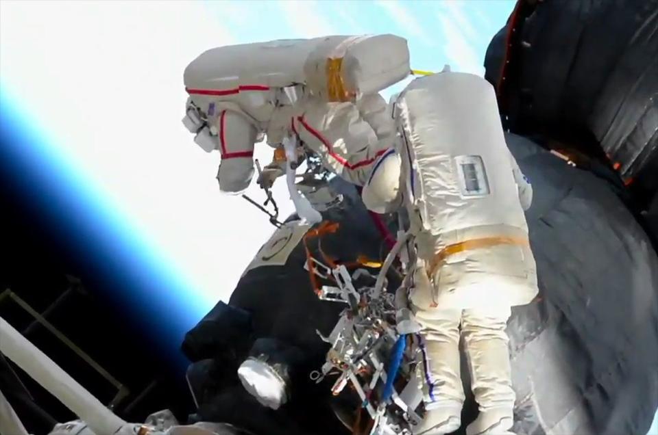 Another look at Kononenko (in the spacesuit with red stripes) and Sergey Prokopyev (with blue stripes), cutting into the exterior insulation of the Soyuz MS-09 spacecraft during a Dec. 11. 2018 spacewalk. <cite>NASA TV</cite>