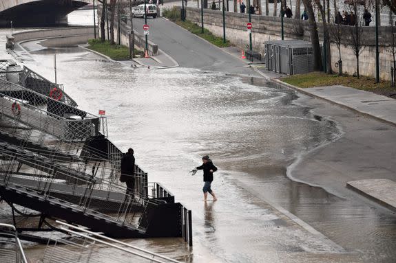 A man holds his shoes in his hands as he walks through the Seine after it burst its banks in Paris.