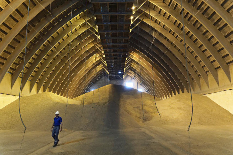 A worker walks past large piles of wheat grain at a storage facility in Ukraine.