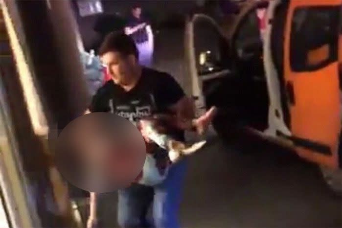 A man pictured carrying a wounded boy away from the scene of the airport attack. Photo: Twitter.