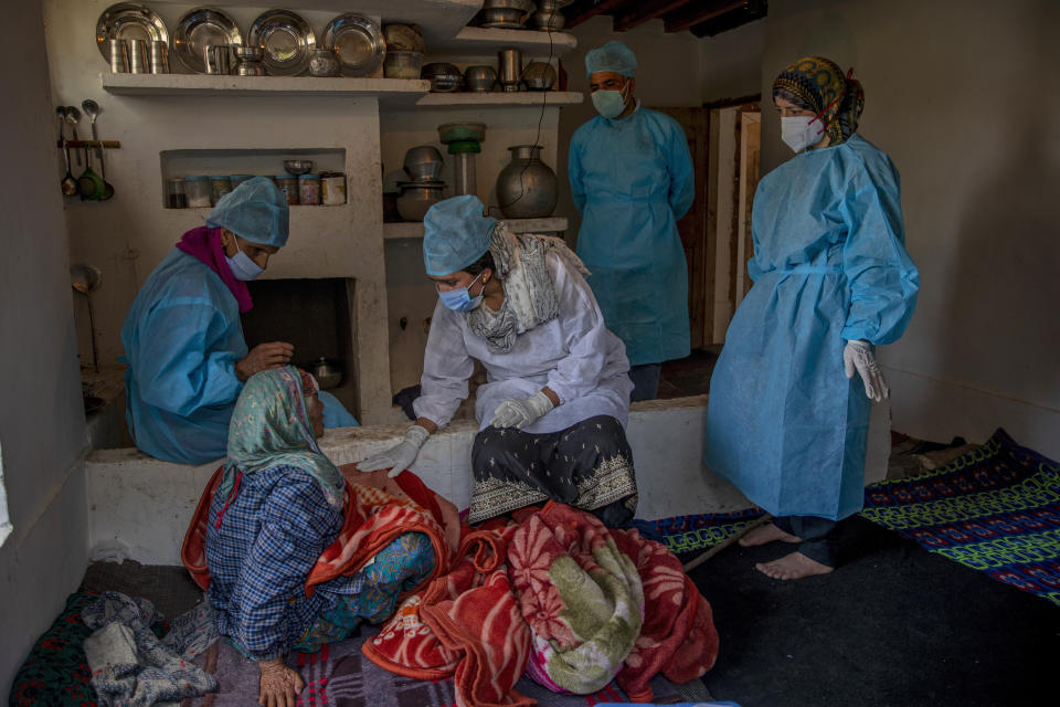 FILE - Health workers talk to Khatija, an elderly tribal woman, to persuade her to take the COVID-19 vaccine in Doodkulan village south of Srinagar, Indian controlled Kashmir, on June 5, 2021. The World Health Organization said Friday May 5, 2023 that COVID-19 no longer qualifies as a global emergency, marking a symbolic end to the devastating coronavirus pandemic that triggered once-unthinkable lockdowns, upended economies and killed millions of people worldwide. (AP Photo/ Dar Yasin, File)