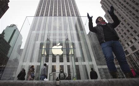 A man poses for a photo in front of the Apple store on 5th Avenue in New York, December 26, 2013. REUTERS/Carlo Allegri