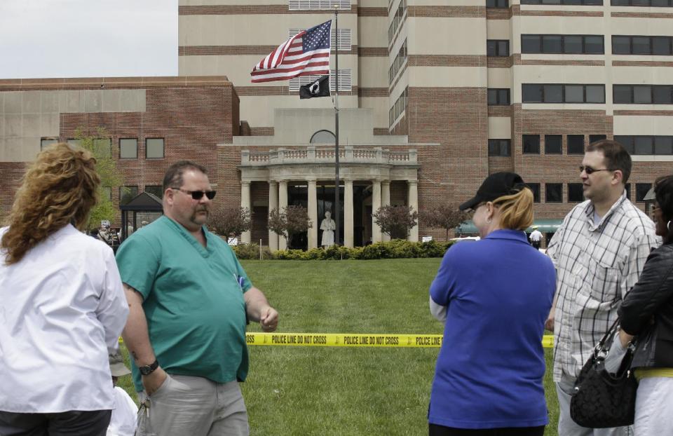 People wait outside a Veterans Affairs hospital after they were evacuated, Monday, May 5, 2014, in Dayton, Ohio. A city official says a suspect is in police custody after a shooting at the Veterans Affairs hospital that left one person with a minor injury. (AP Photo/Al Behrman)
