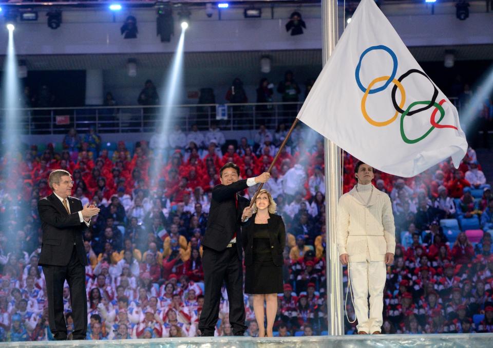 International Olympic Committee President Thomas Bach, left, applauds as Lee Seok-rai, mayor of Pyeongchang, waves the Olympic flag during the closing ceremony of the 2014 Winter Olympics, Sunday, Feb. 23, 2014, in Sochi, Russia. (AP Photo/Jung Yeon-je, Pool)