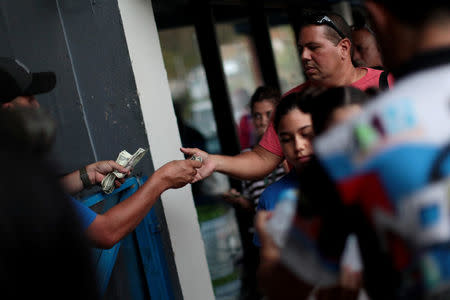 A local resident pays cash as he buys ice at a local ice factory weeks after Hurricane Maria hit Puerto Rico in Orocovis, Puerto Rico, October 6, 2017. REUTERS/Alvin Baez