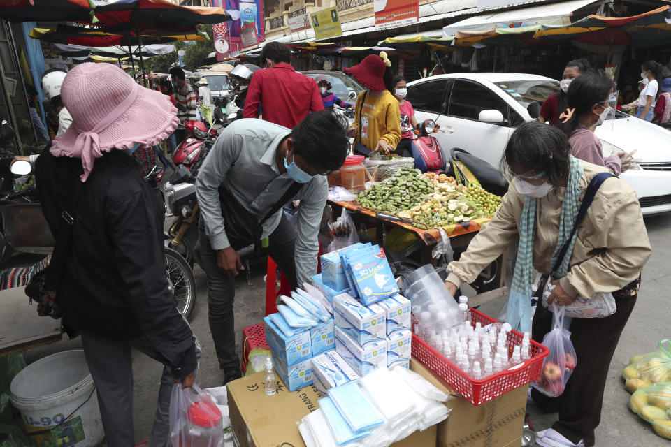 A customer, right, wears a protective face mask to prevent the spread of the coronavirus, buys items at a local market outside Phnom Penh, Cambodia, Saturday, April 10, 2021. (AP Photo/Heng Sinith)