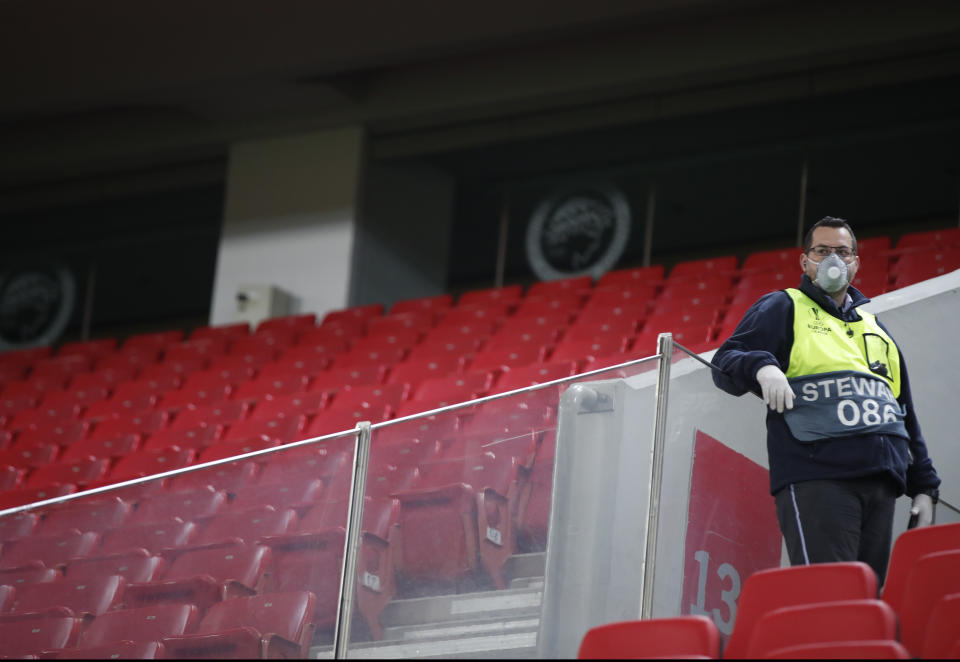 Un empleado de seguridad monta guardia con un cubrebocas en el graderío sin público, antes del encuentro de la Liga Europa entre Olympiakos y Wolverhampton Wanderers, el jueves 12 de marzo de 2020 (AP Foto/Thanassis Stavrakis)