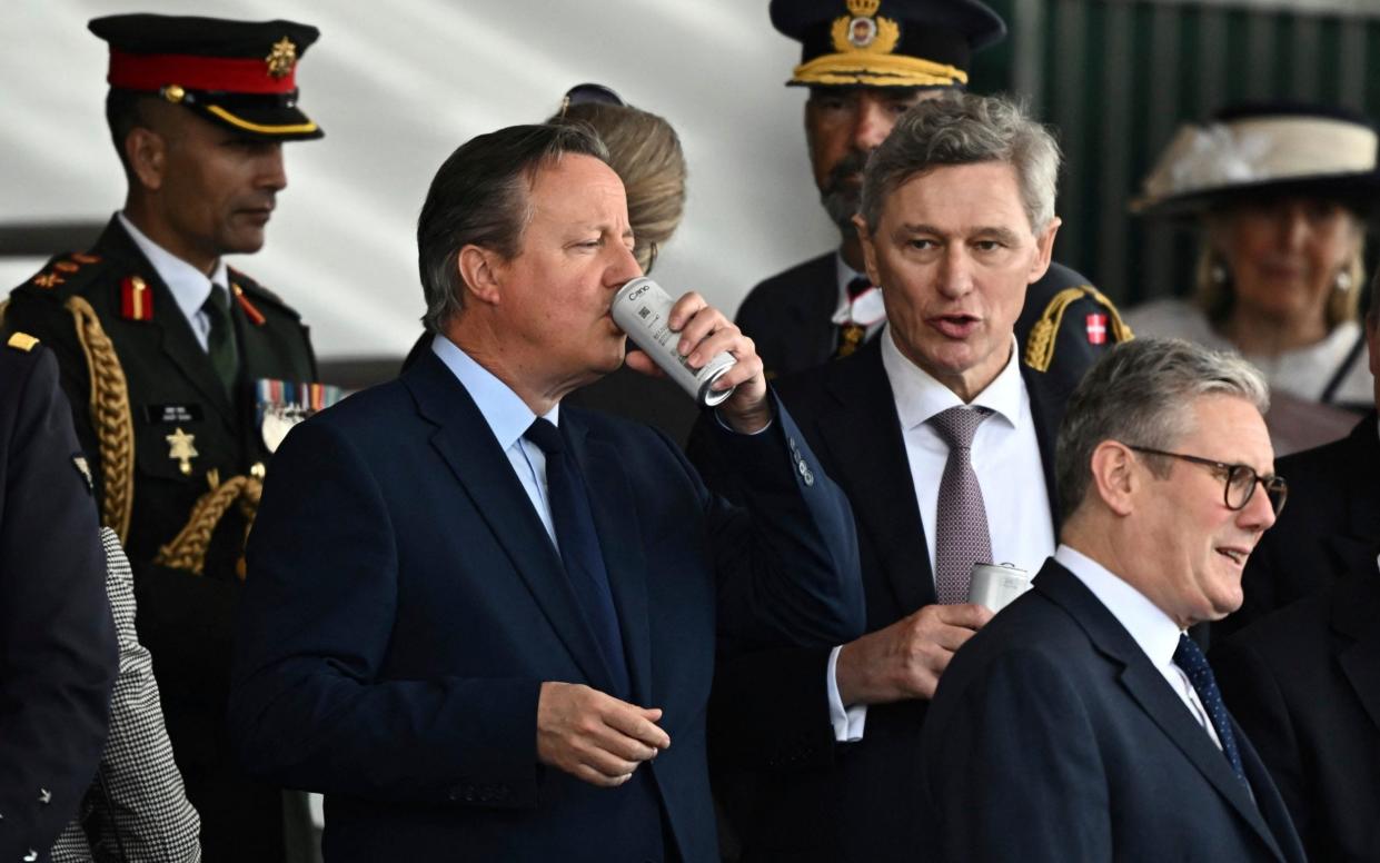 British Foreign Secretary David Cameron drinks from a can next to Labour Party leader Keir Starmer on the day of a commemorative event for the 80th anniversary of D-Day,