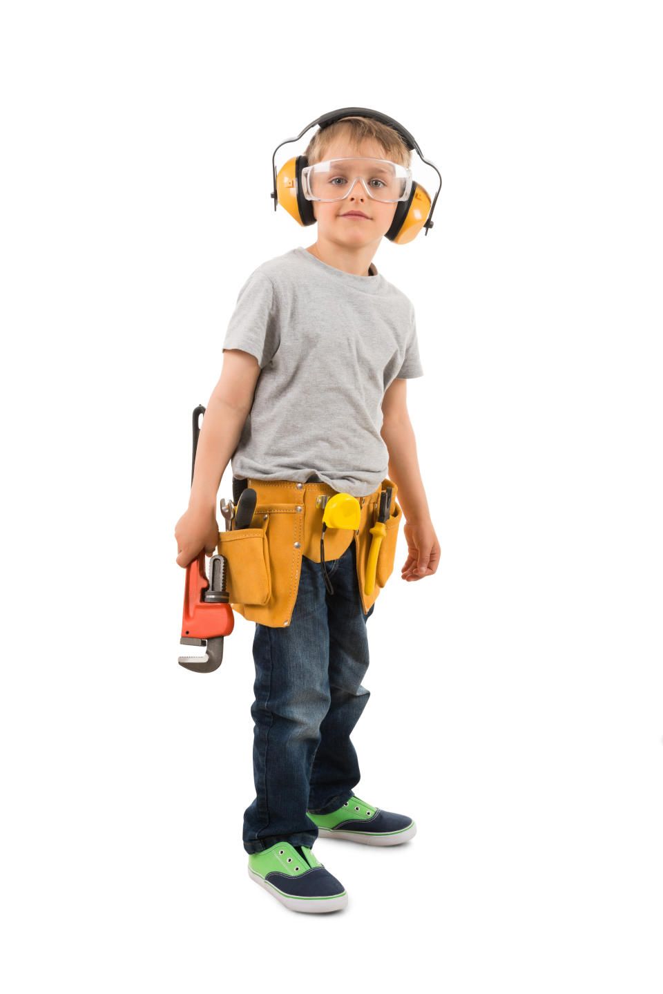 Child wearing safety glasses, earmuffs, a gray T-shirt, jeans, green sneakers, and a tool belt with a wrench, poses against a white background