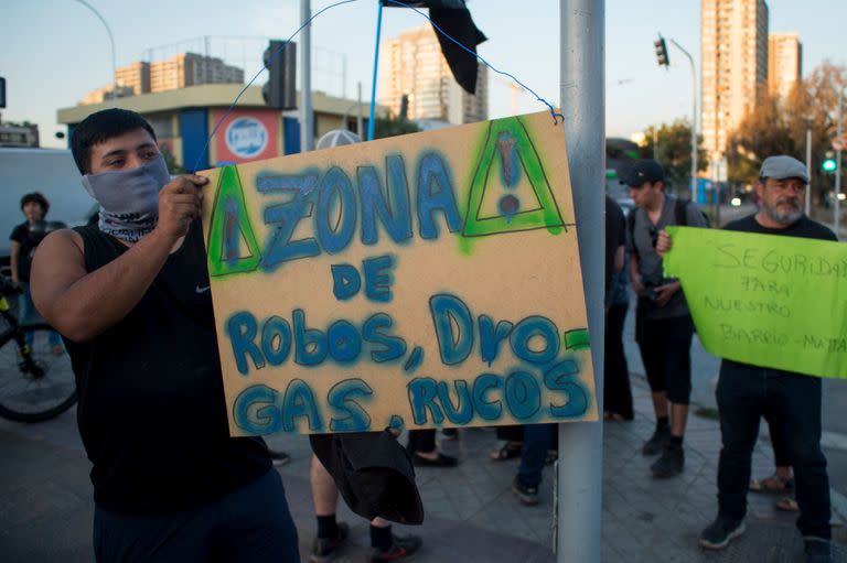 Un manifestante sostiene un cartel en el que se lee "Zona de robos, drogas, rucos" durante una protesta en el Barrio Matta de Santiago el 29 de marzo de 2023.