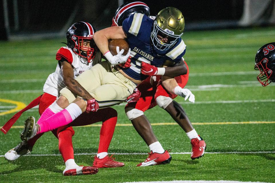 Salesianum senior Hunter Balint (19) holds on to the ball as William Penn juniors Zion Pitts (13) and Samari Hampton (9) wrap him up for the takedown during the football game at Abessinio Stadium in Wilmington, Friday, Oct. 13, 2023. Salesianum won 49-0.