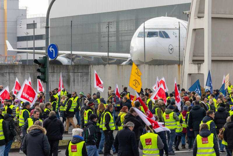 Strikers march from the Lufthansa Aviation Center to Terminal 1 with banners and Verdi flags during a protest.  With renewed warning strikes by several professional groups, the Verdi union is paralyzing important parts of German air traffic on Thursday and Friday. Lando Hass/dpa