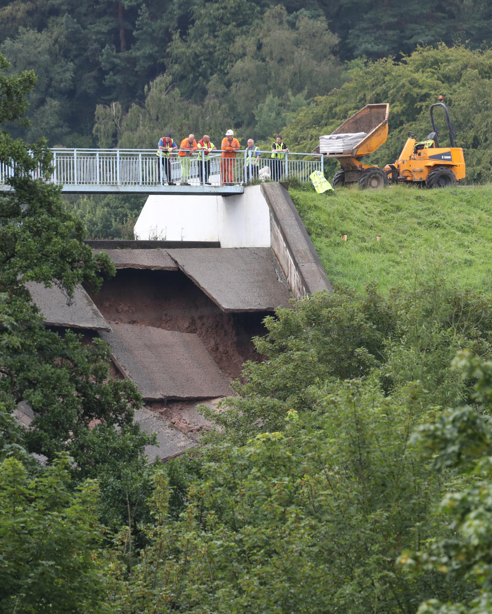 A team of men look at the damage to the wall of Toddbrook Reservoir near the village of Whaley Bridge, Cheshire, after it was damaged in heavy rainfall.