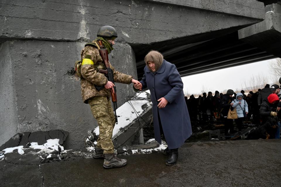 A Ukrainian soldier holds the hand of an elderly woman as he helps her evacuate Irpin. 