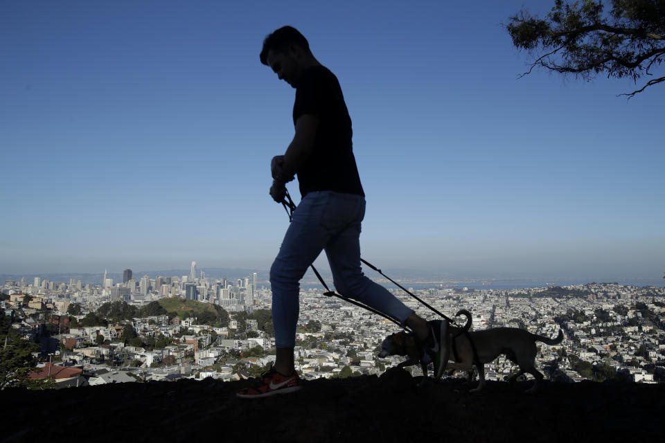 Fabian Jimenez walks his dogs atop Tank Hill in San Francisco, Wednesday, Feb. 26, 2020. California officials are bracing for the potential of another drought and an early and more intense wildfire season amid a record-breaking warm and dry February. (AP Photo/Jeff Chiu)