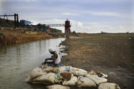 In this Wednesday, July 17, 2019, photo, an Indian fixes bait for fish, sitting on the dried up bed of Red Hills lake, a 4,500-acre 19th-century reservoir, in Chennai, capital of the Southern Indian state of Tamil Nadu. In Chennai, a coastal city of about 10 million and the capital of Tamil Nadu state, rapid development and rampant construction have overtaxed a once-abundant natural water supply, forcing the government to spend huge sums to desalinate sea water, bring water by train from hundreds of kilometers (miles) away and deploy an army of water trucks to people whose household taps have suddenly run dry. (AP Photo/Manish Swarup)