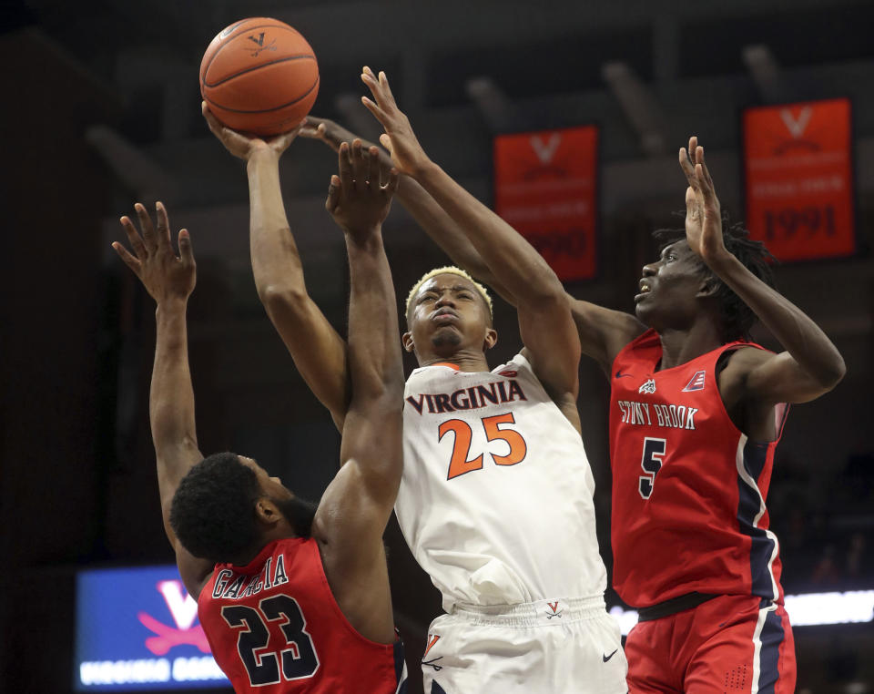 Virginia forward Mamadi Diakite (25) shoots between Stony Brook guard Andrew Garcia (23) and forward Mouhamadou Gueye (5) during an NCAA college basketball game in Charlottesville, Va., Wednesday, Dec. 18, 2019. Virginia won 56-44. (AP Photo/Andrew Shurtleff)