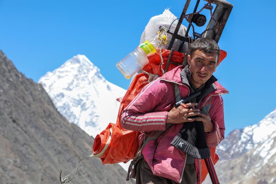 A porter is seen trekking past K2.