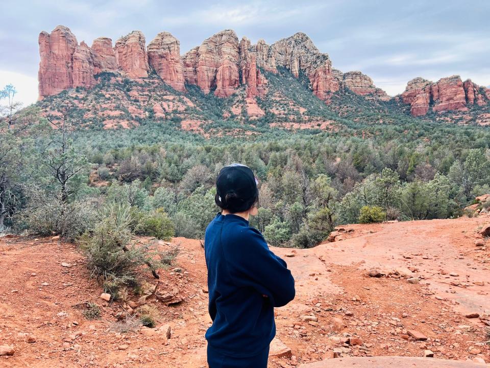 A woman with her back turned to admire red rock formations.