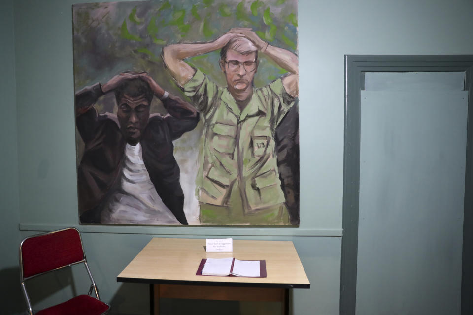 In this Sept. 26, 2019, photo, a painting of one of the images of the takeover of U.S. Embassy in Tehran in 1979 which shows U.S. Marine Sgt. Ladell Maples of Earle, Ark., left, and Cpl. Steve Kirtley of Little Rock, Ark., with their hands above their heads adorns a wall of the embassy, now partly a museum, in Tehran, Iran. Images like those of surrendering American troops carry a strong resonance for hard-liners in Iran. (AP Photo/Vahid Salemi)